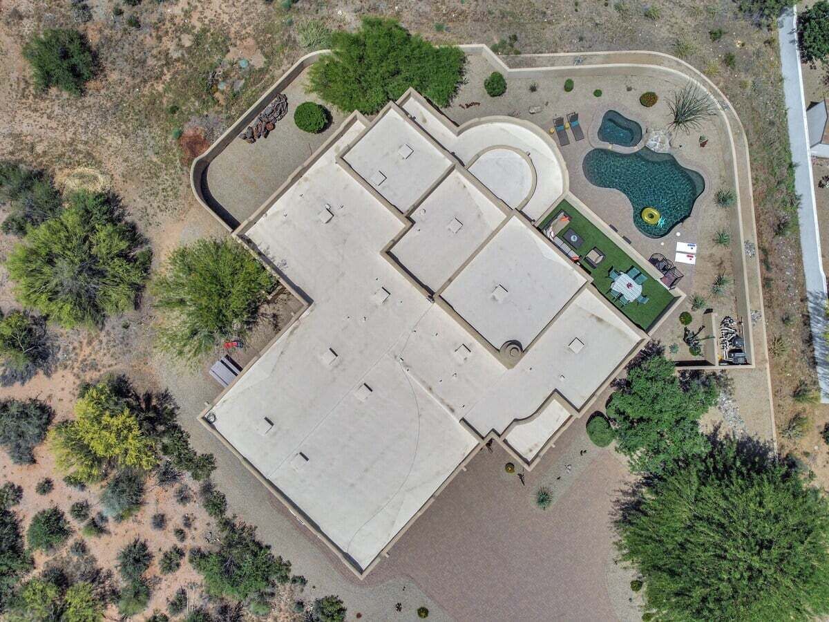 Ein Luftbild eines Gebäudes mit einer großen, flachen Dachterrasse, umgeben von Grünflächen und einem Schwimmbad.
