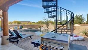 Ein Poolbereich mit Wendeltreppe, Grill, Liegestühlen und Whirlpool.