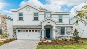 A two-story house with a garage, stone facade, and a well-maintained front yard with shrubs. - Hzd9088 (Davenport)