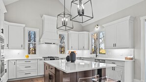 Una cocina moderna con armarios blancos, una isla central e iluminación colgante.