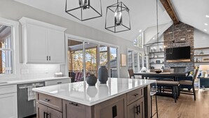 Una cocina moderna con armarios blancos, una isla central y una chimenea de piedra.