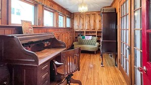 A room with wooden paneling, a piano, a green sofa, and a red door. - Kurtz Cottage - Y856 (York Beach)