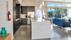 A modern kitchen with dark cabinets, stainless steel appliances, and a central island. - Lucent (Palm Springs)