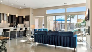 A modern kitchen with dark cabinets, a central island, and pendant lighting. - Lucent (Palm Springs)