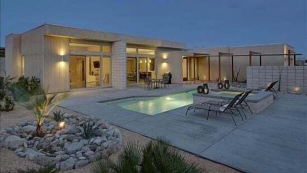 A modern house with a swimming pool, outdoor seating, and a well-lit patio area. - Lucent (Palm Springs)