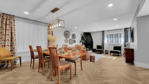 A modern living room with a wooden dining table, chairs, a fireplace, and a TV mounted on the wall. - Los Lagos Mesa (Mesa)