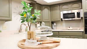 A kitchen with green cabinets, a microwave, a sink, and a decorative plant on the counter. - Los Lagos Mesa (Mesa)
