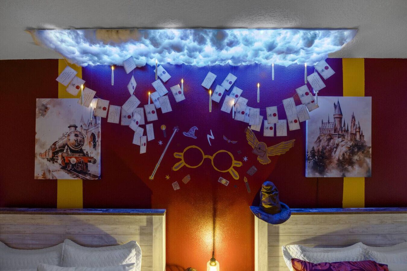 Ein Zimmer mit einer Wandmalerei von Wolken, Spielkarten und einem Schlossgemälde.
