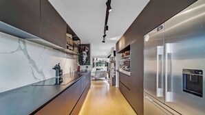 Eine moderne Küche mit einem Edelstahl-Kühlschrank, Marmor-Spritzschutz und Holzböden.