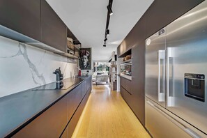 Een moderne keuken met een roestvrijstalen koelkast, een marmeren achterwand en houten vloeren.