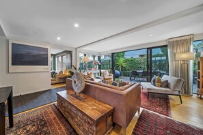 Een moderne woonkamer met een bank, salontafel en een groot raam met uitzicht op de omgeving.