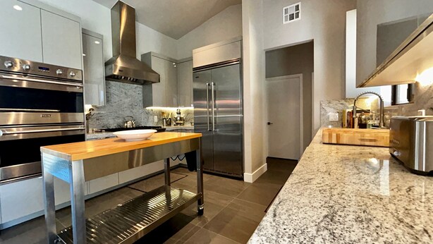 A modern kitchen with stainless steel appliances, a marble countertop, and a central island.