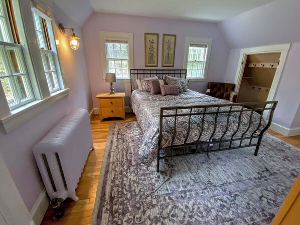 Une chambre à coucher comprenant un lit, une table de chevet, une lampe, un radiateur et une armoire.