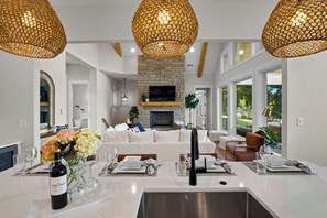 A modern living room with a stone fireplace, white sofas, and a dining area with a white table set for six. - Hogan Crest (Mooresville)
