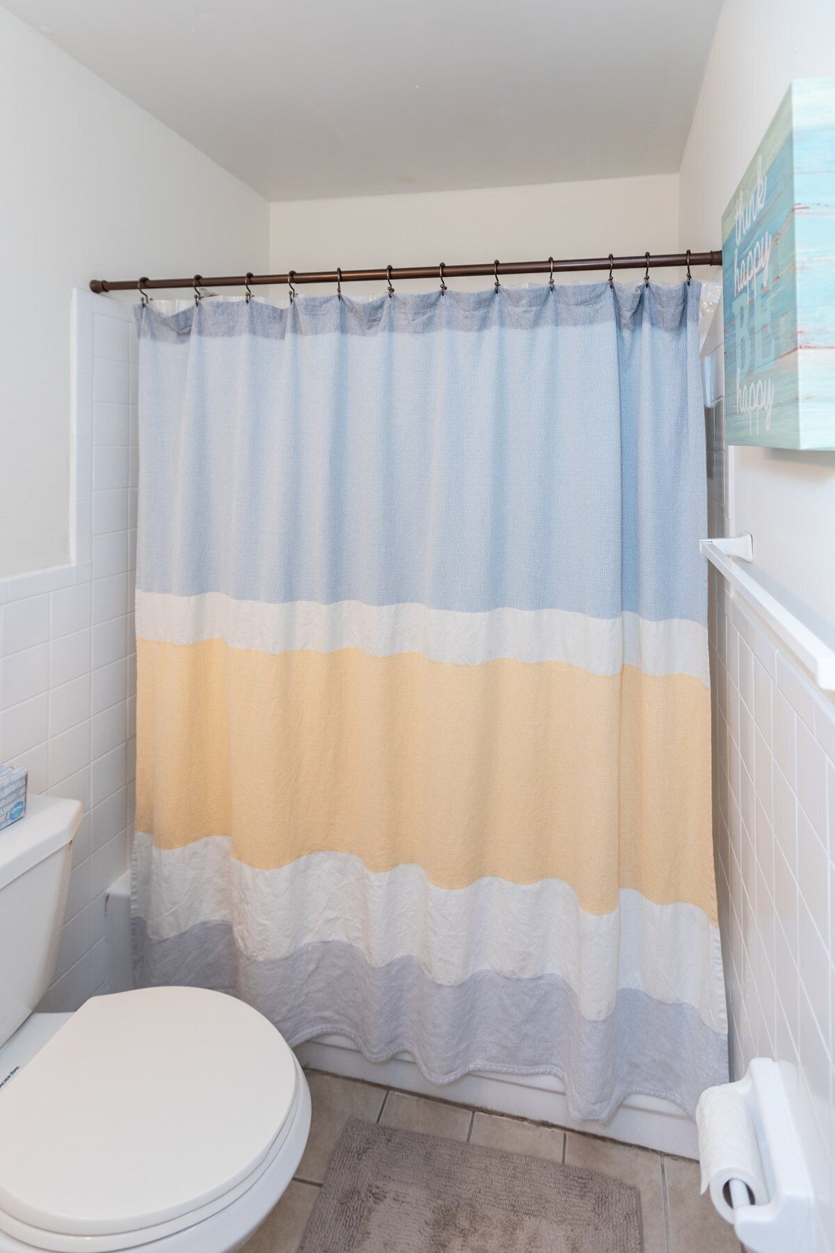 Une salle de bain avec un rideau de douche à rayures, des toilettes et un porte-serviettes.