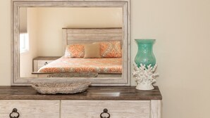 A bedroom with a bed, a dresser, a mirror, and a vase. - Latitude Adjustment (Virginia Beach)