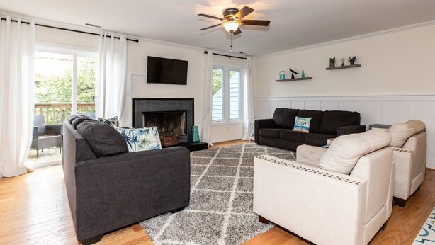 A living room with a fireplace, two sofas, a ceiling fan, and a view of the outdoors. - Latitude Adjustment (Virginia Beach)