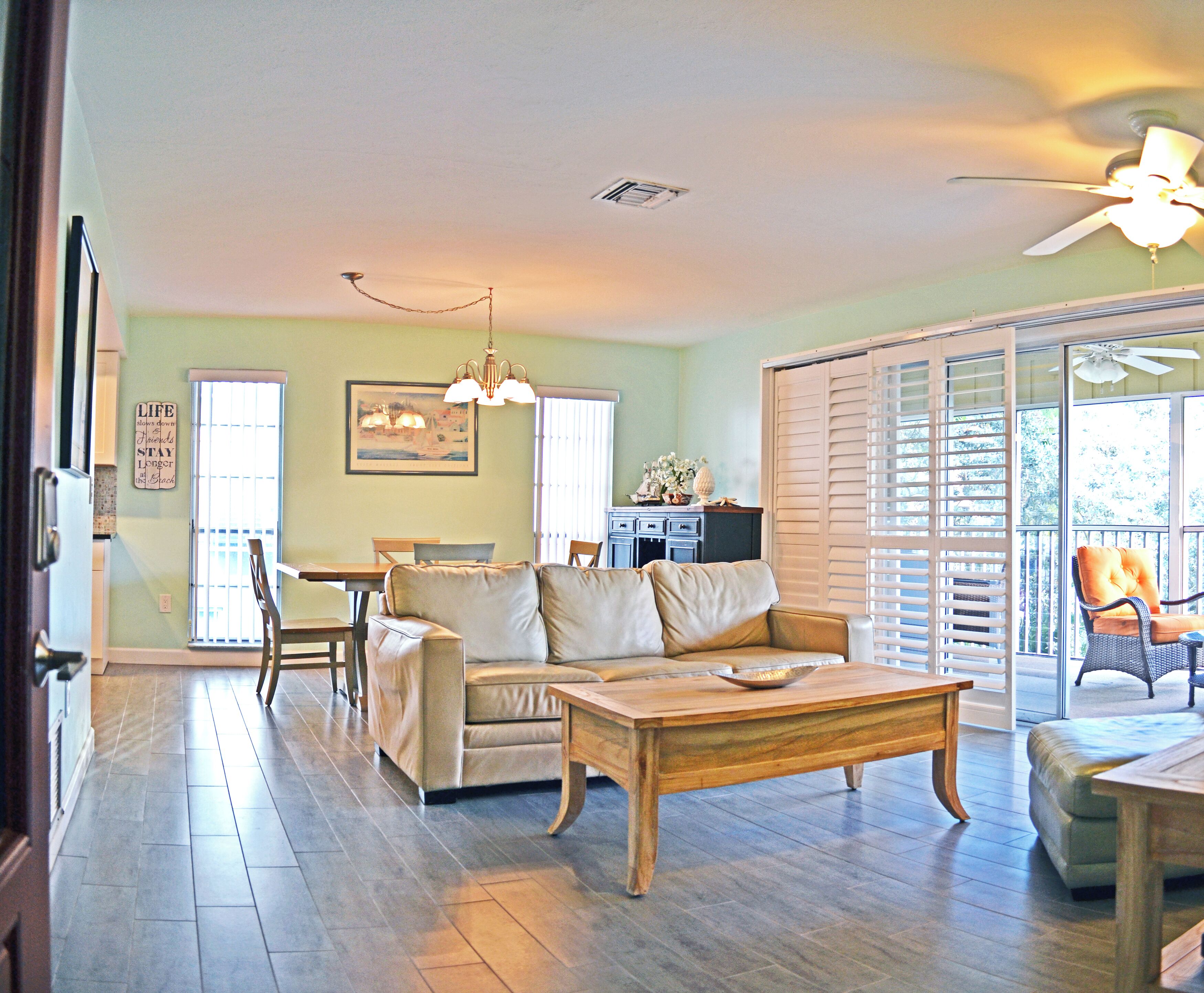 A spacious living room with a wooden coffee table, a beige sofa, and a dining area with a table and chairs.