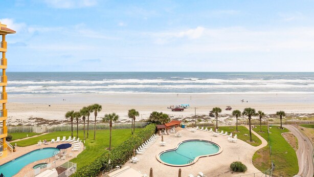 Een resort met zwembad, uitzicht op het strand en palmbomen.
