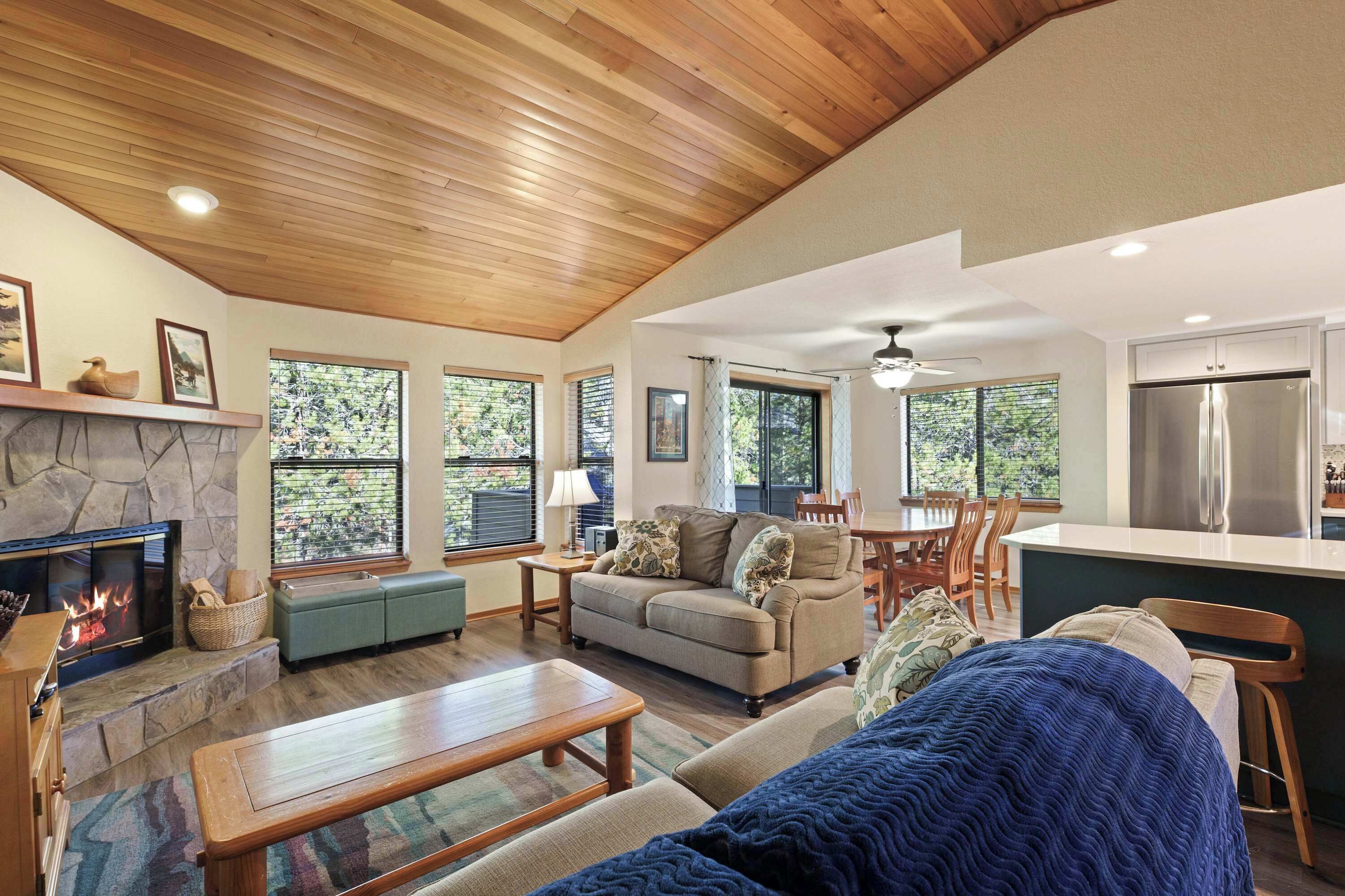A spacious living room with a fireplace, a sofa, a coffee table, and a dining area with a kitchen in the background.