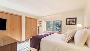 Quarto com cama, escrivaninha, janela com persianas e porta.