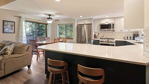 Uma cozinha moderna com uma ilha grande, cadeiras de madeira e uma mesa de jantar.