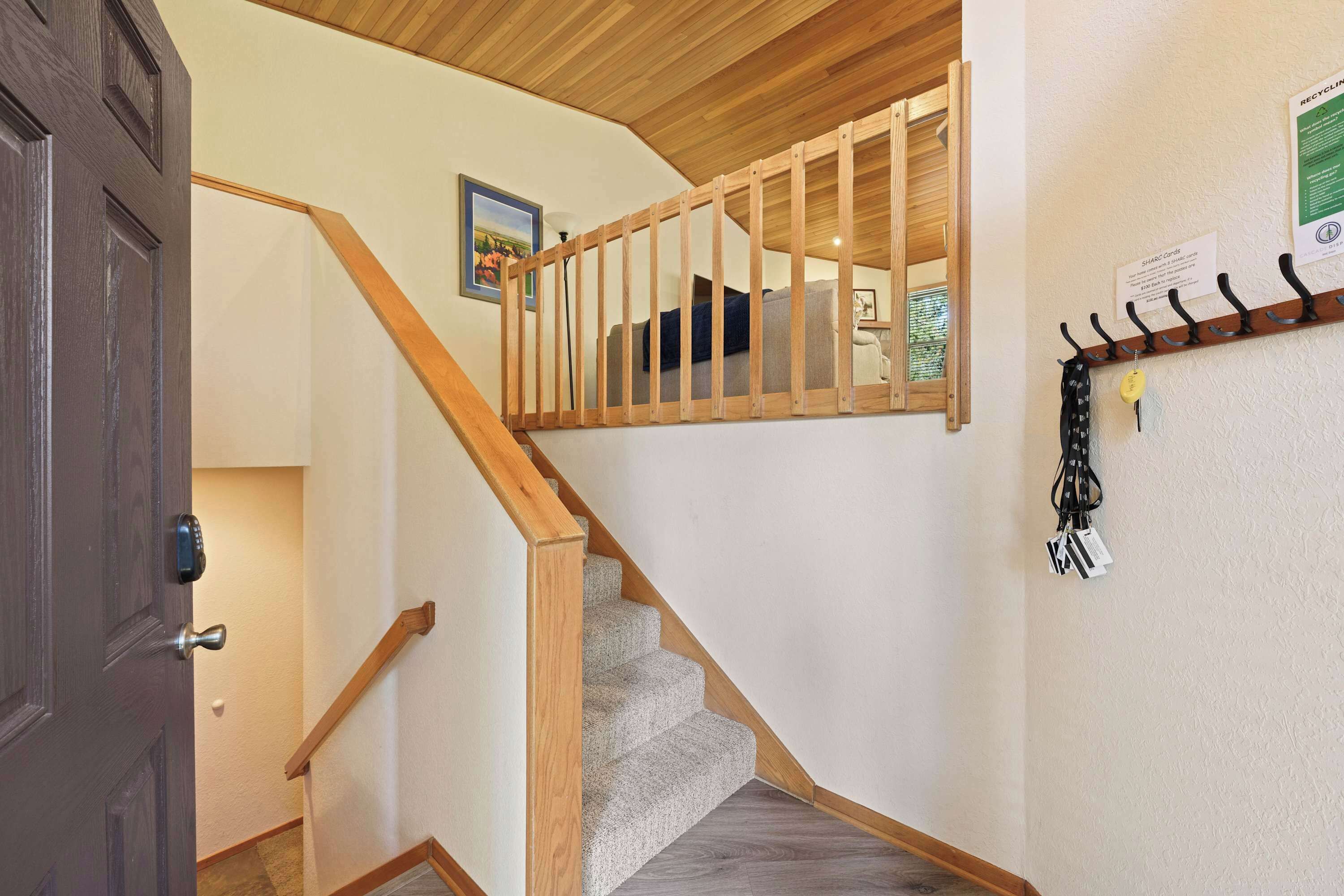 A wooden staircase with a handrail, a coat rack with hangers, and a door with a key lock.