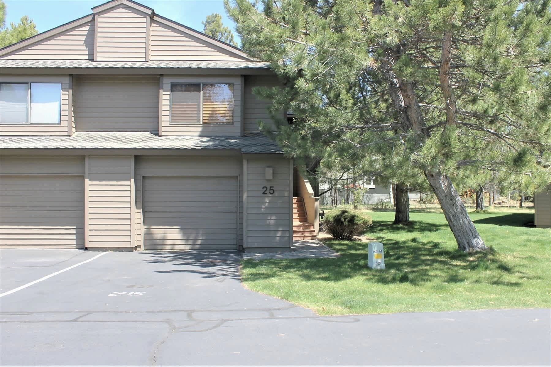 A two-story building with a garage, number 25, and a tree in front.
