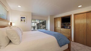 A bedroom with a bed, a window, a wooden wardrobe, and a framed picture on the wall. - Fairway Village 8 (Bend)