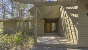 A covered outdoor area with a wooden door and a small porch. - Goldfinch 18 (Bend)