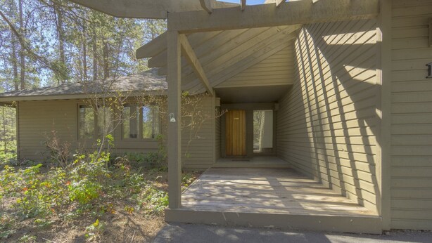 A covered outdoor area with a wooden door and a small porch. - Goldfinch 18 (Bend)