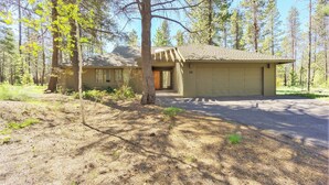 A single-story house with a garage, surrounded by trees and a clear sky. - Goldfinch 18 (Bend)