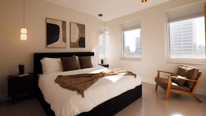 A modern bedroom with a large bed, a wooden chair, and artwork on the wall. - Exclusive Midtown Luxury Step From Times Square! (New York)