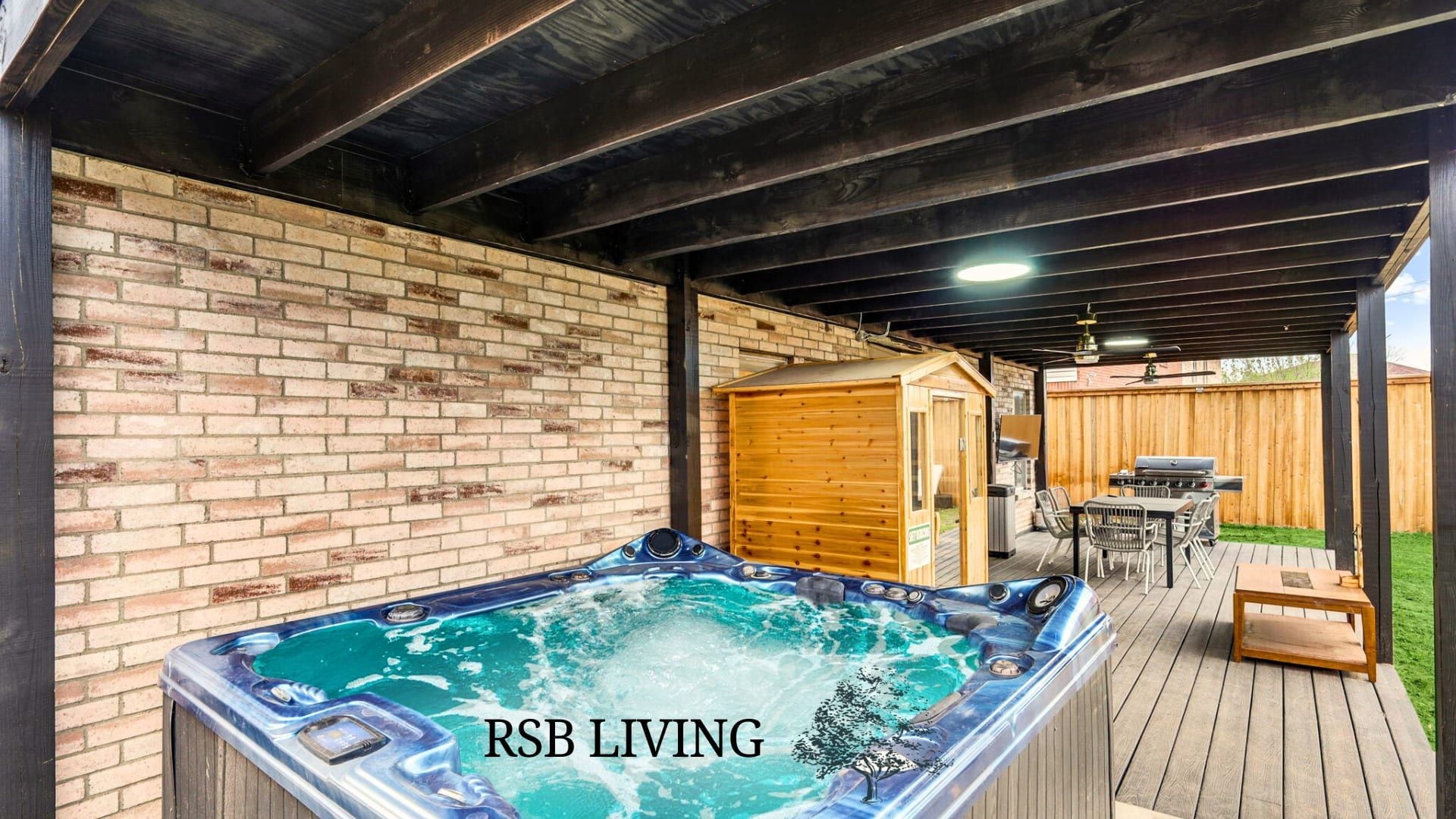 A hot tub under a wooden pergola with a brick wall and a wooden shed in the background.