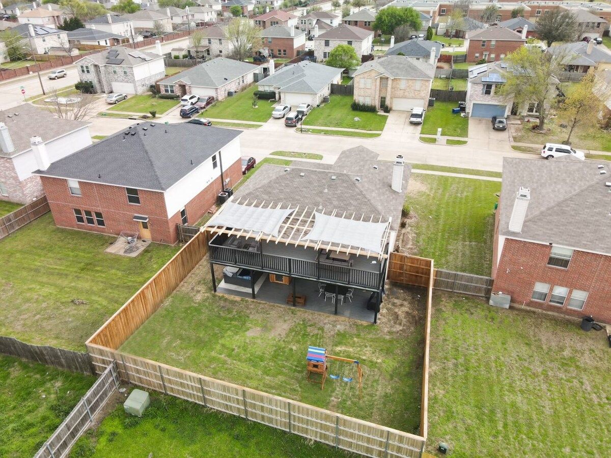 A residential area with a house featuring a covered patio, a fenced yard, and a small swing set.