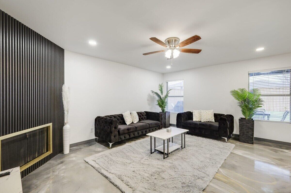 A modern living room with a sectional sofa, a coffee table, and a ceiling fan.