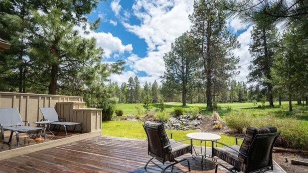 Eine Holzterrasse mit Gartenmöbeln, einem kleinen Tisch und Stühlen.