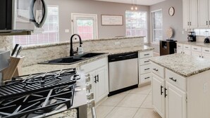Una cucina moderna con piani in granito, elettrodomestici in acciaio inossidabile e mobili bianchi.