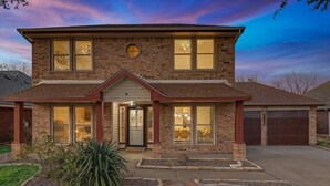 A two-story house with a brick facade, a front porch, and a driveway. - Glamorous 4BR 2B Home With Pool, Game Room & Fire Pit (Mesquite)