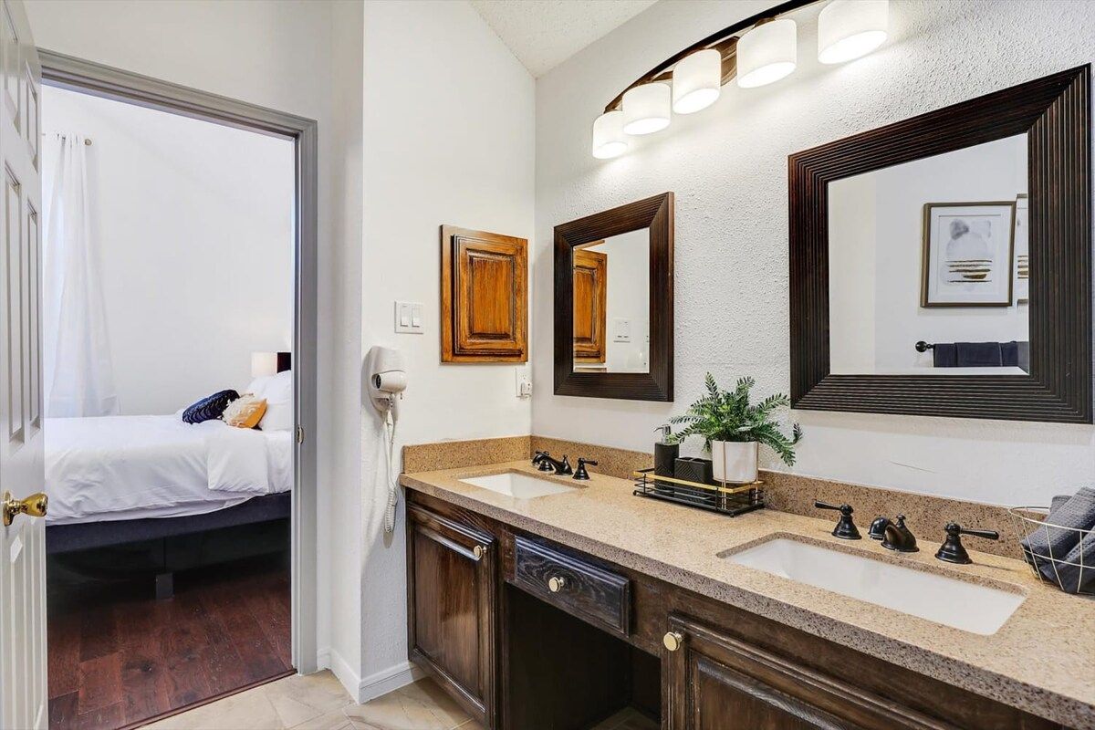 A bathroom with a double sink, a mirror, a towel rack, and a shower curtain.