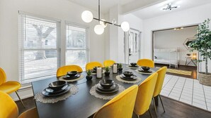 A dining area with a dark table, yellow chairs, and a modern chandelier. - Glamorous 4BR 2B Home With Pool, Game Room & Fire Pit (Mesquite)
