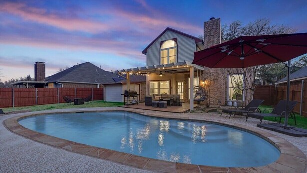 A backyard with a swimming pool, patio furniture, and a covered seating area. - Glamorous 4BR 2B Home With Pool, Game Room & Fire Pit (Mesquite)
