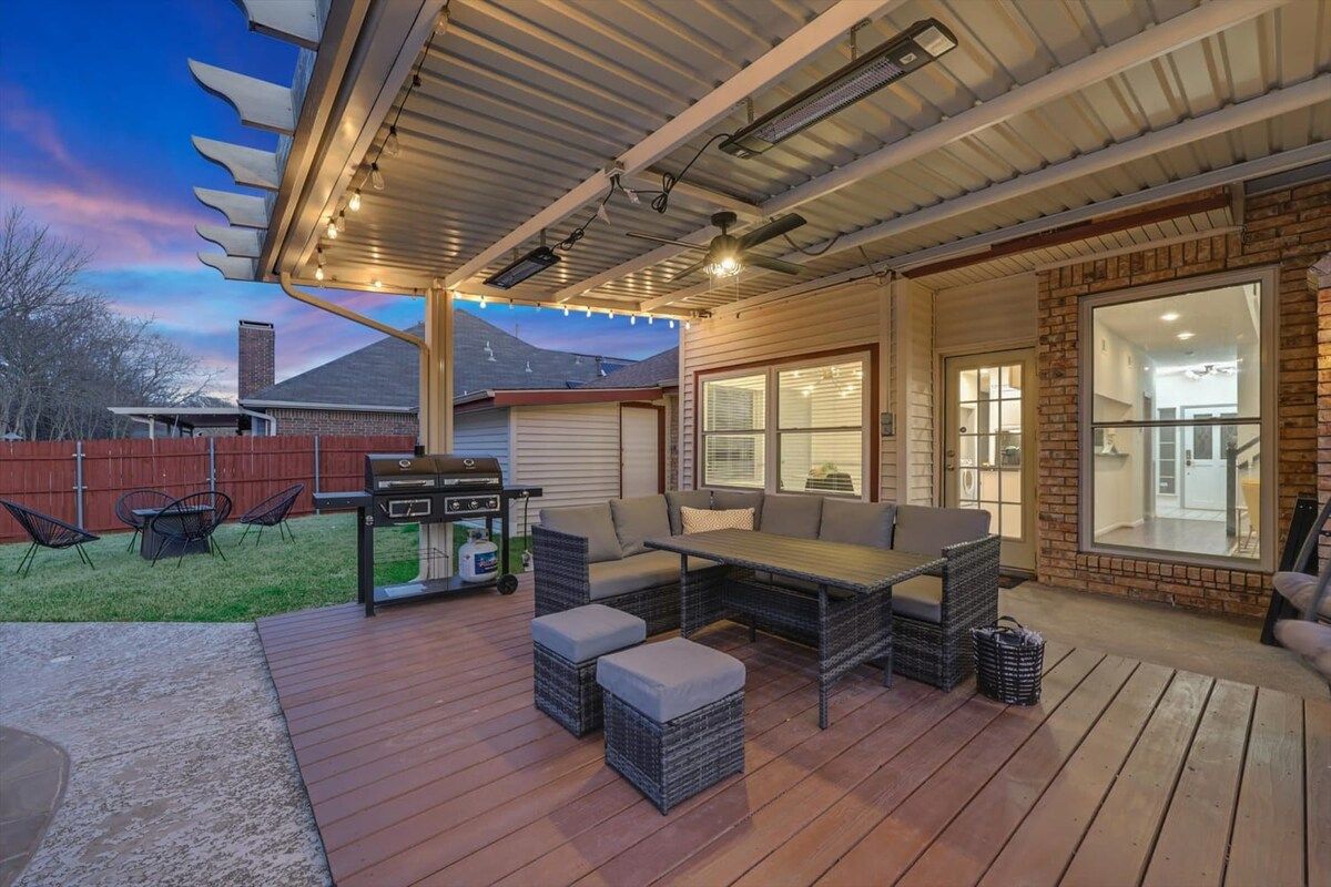 An outdoor patio with a grill, seating area, and large windows.