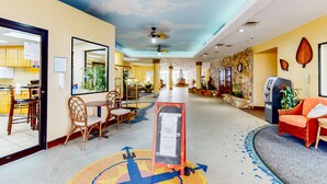 A hotel lobby with a ceiling mural, a reception desk, a seating area, and a staircase leading to the upper floor. - Harbour Beach Resort 518 (Daytona Beach)