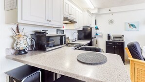 A compact kitchen with white cabinets, a microwave, a stove, and a toaster. - Harbour Beach Resort 518 (Daytona Beach)