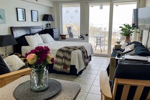 A hotel room with a bed, a desk with a laptop, a balcony with a view of the sea, and a TV mounted on the wall. - Harbour Beach Resort 518 (Daytona Beach)