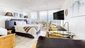 A modern hotel room with a bed, a desk, a sofa, and a balcony with a view. - Harbour Beach Resort 518 (Daytona Beach)