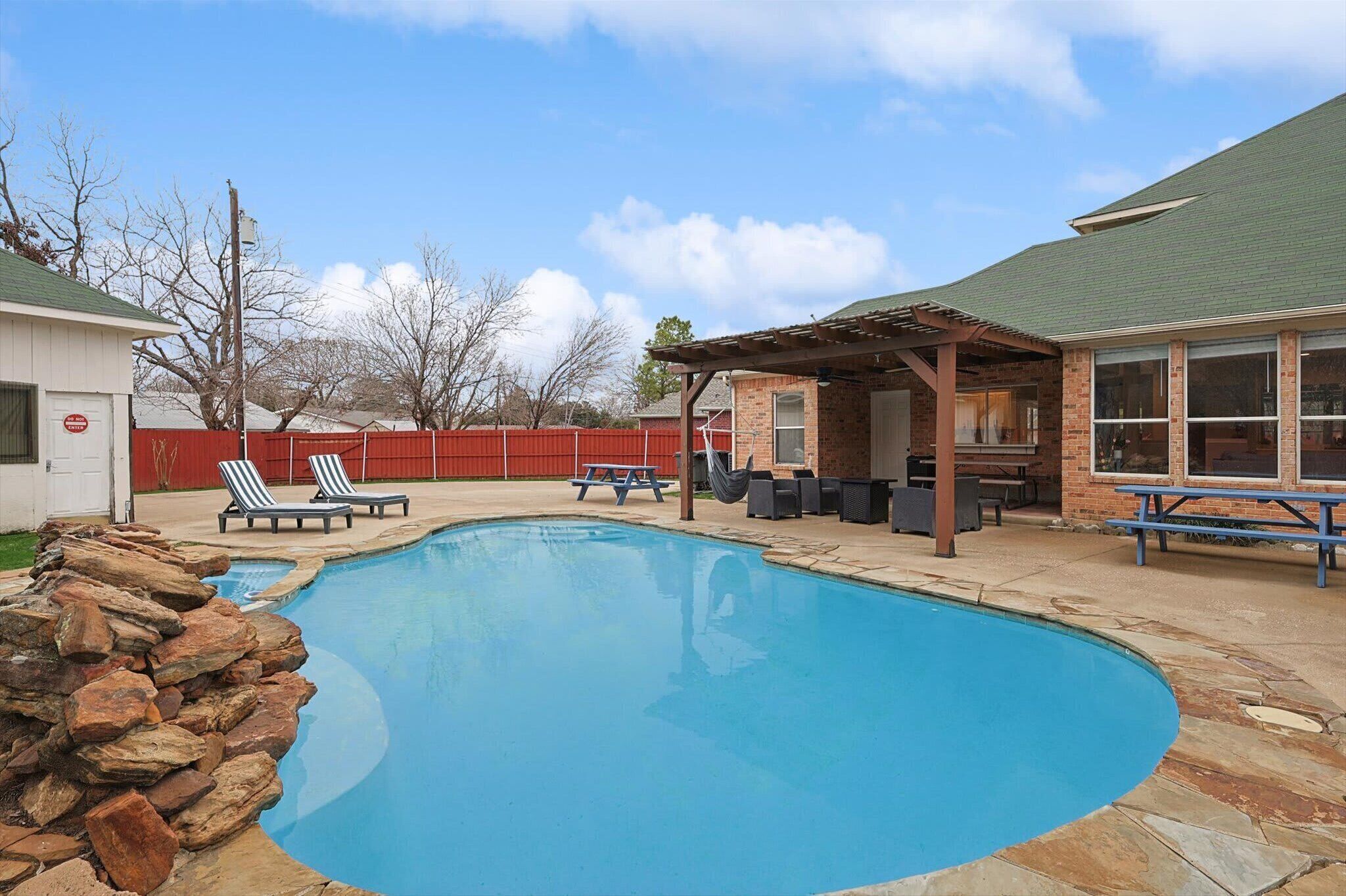 A swimming pool with lounge chairs and a covered patio area.