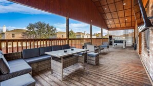 Une terrasse extérieure couverte, aménagée avec des sièges, une table et un espace barbecue.