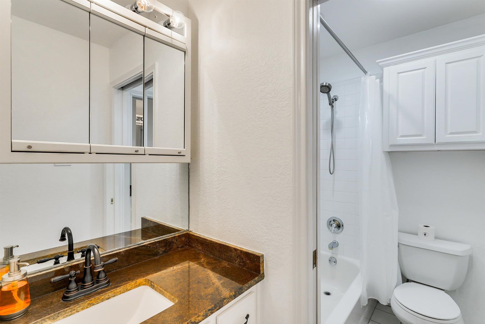 Une salle de bain équipée d’un lavabo, d’un miroir, d’une douche, de toilettes et de placards.
